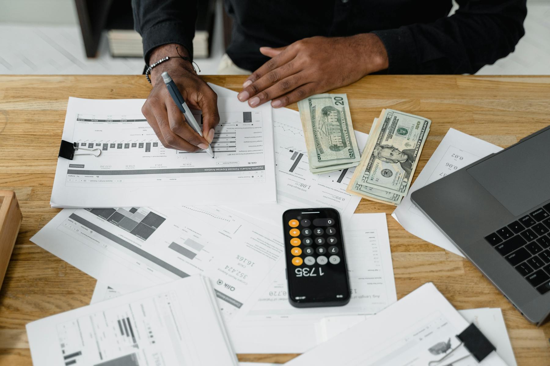 Financial reports, calculator, laptop, and business paperwork on a desk